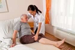 caregiver helping an old man getting up in bed